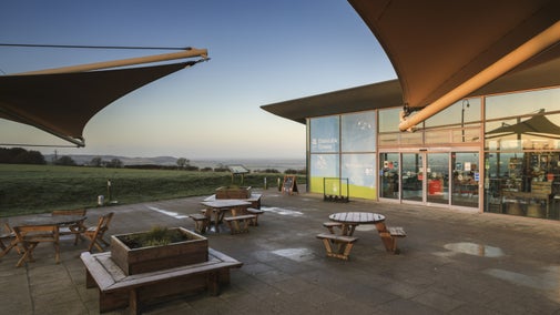 a building on the left with benches on the right. it is low light with a clear sky and frosty